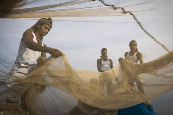 Fishermen in Bangladesh skillfully handle large fishing nets under a clear sky. | © GIZ Ranak Martin