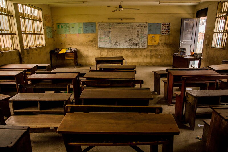 An empty classroom with wooden desks and a whiteboard reflects the impact of Covid-19 on education.