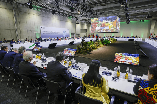 Delegates sit around a large conference table at the Global Forum for Food and Agriculture, discussing sustainable practices.
