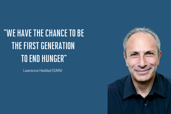 A man smiles beside a motivational quote about ending hunger on a blue background.