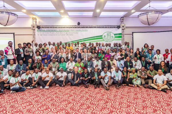 A large group of people pose together at the 2022 regional conference in Lusaka, Zambia, celebrating agricultural finance initiatives.