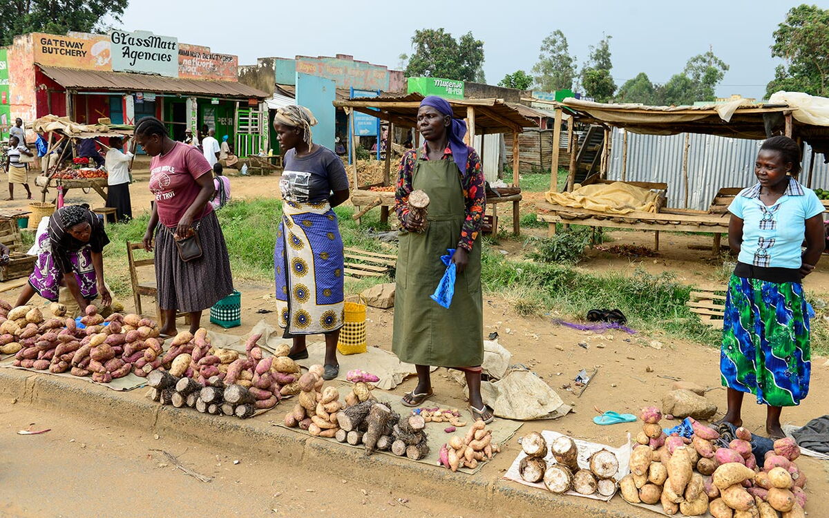 Fünf Frauen verkaufen Süßkartoffeln und andere Knollen auf einem Markt in Kenia.