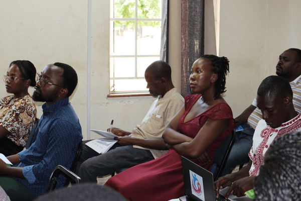 Participants attentively listen during a policy briefing session in a well-lit conference room.