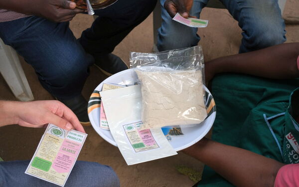 Eine Gruppe von Menschen betrachtet Sojapulver und Verpackungen auf einem Teller.