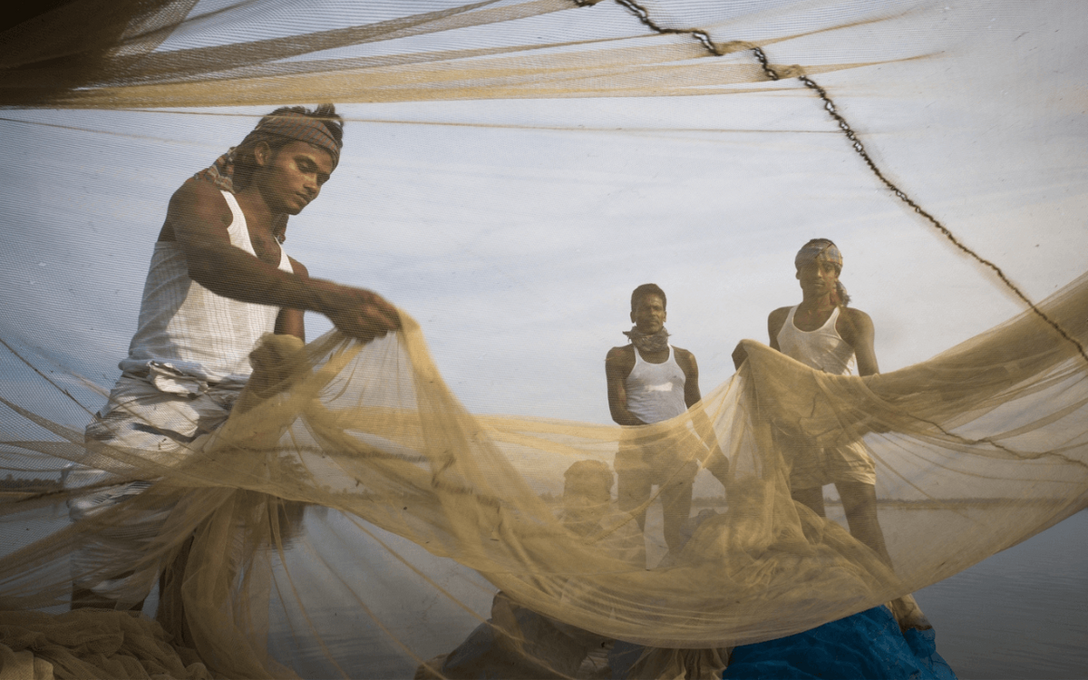 Fischer in Bangladesch entwirren gemeinsam ein großes Netz am Ufer. | © GIZ Ranak Martin