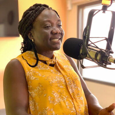 Eine Frau im gelben Kleid spricht in ein Mikrofon während einer Radiosendung zum Internationalen Frauentag 2021.