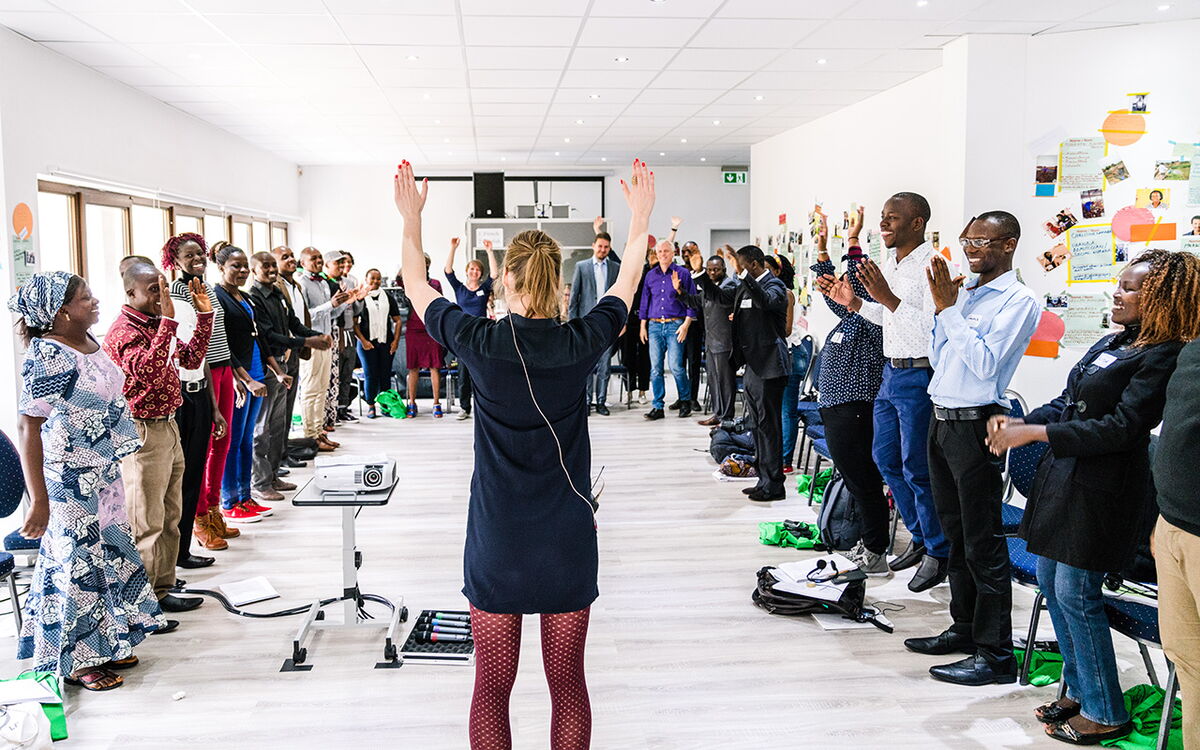 A facilitator leads a diverse group in a dynamic workshop activity, with participants standing in a circle and engaging actively.