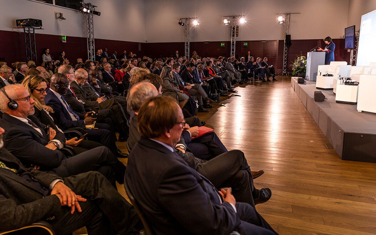 Ein Redner hält eine Präsentation vor einem vollen Saal von Zuhörern bei einer Konferenz.