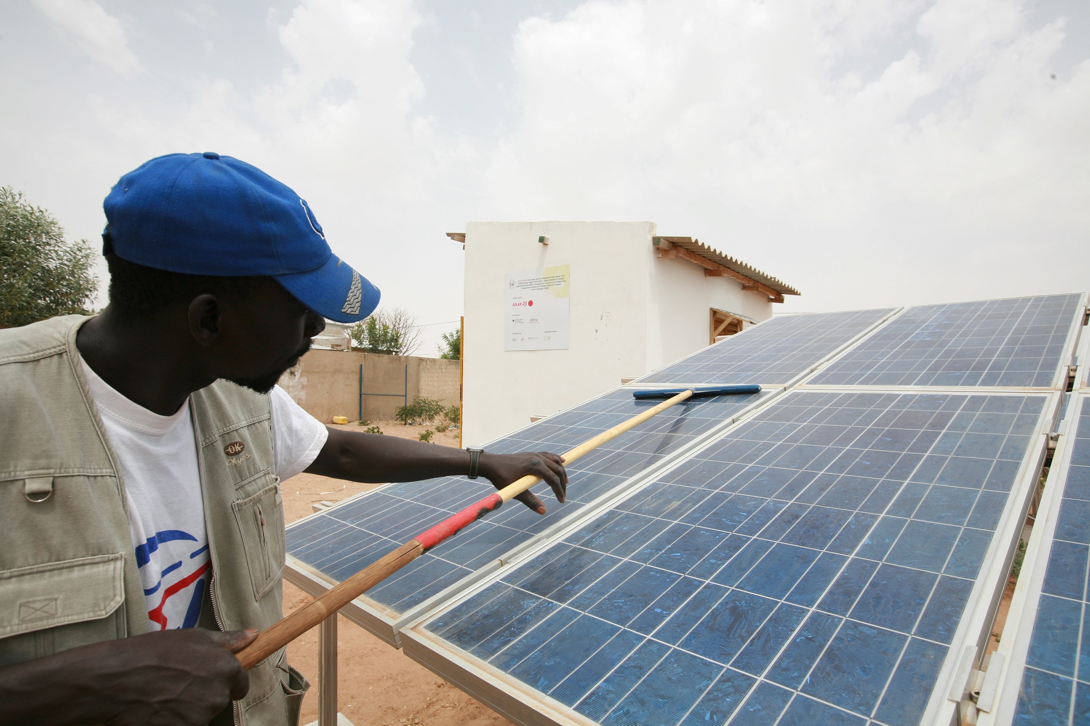 Man cleans solar panel in Senegal. Photo: GIZ/Kamikazz